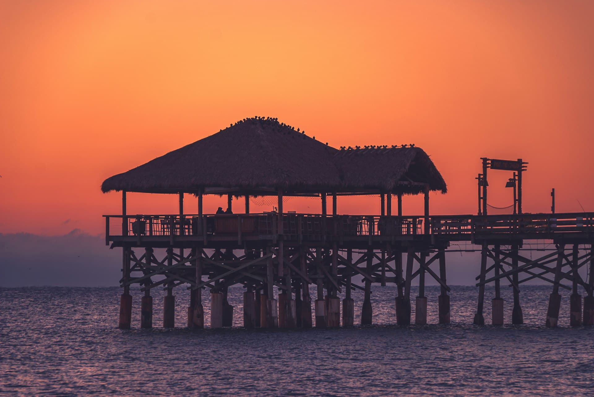 Cocoa Beach Pier silhouetted against an orange sunset