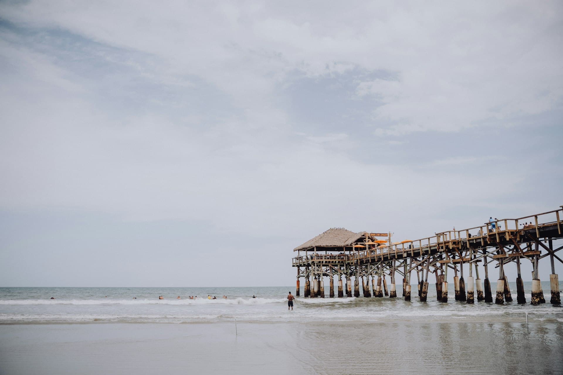 Cocoa Beach Pier with swimmers in the surf on a summer day