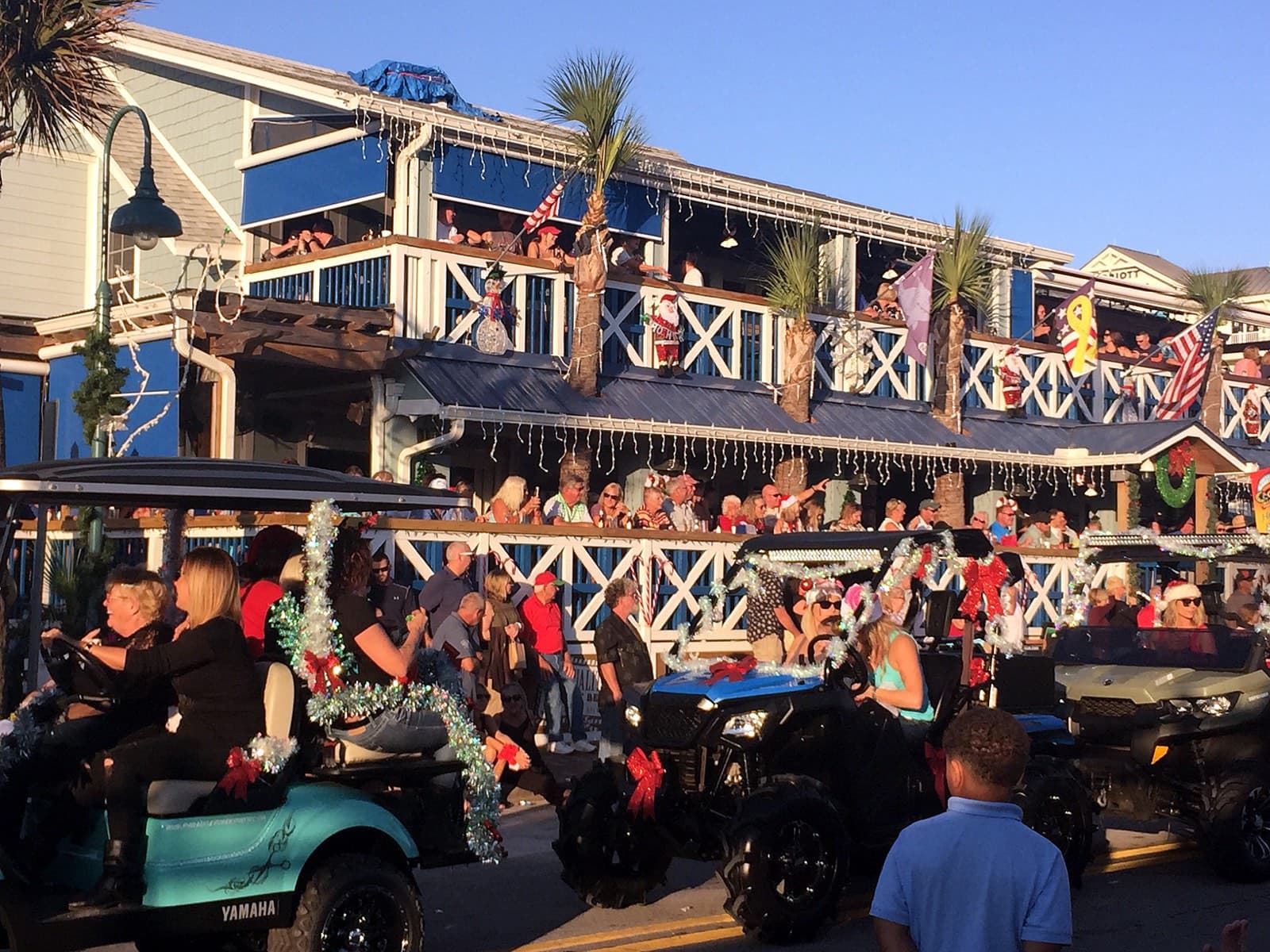 Decorated golf carts and a festive crowd at a holiday parade in New Smyrna Beach