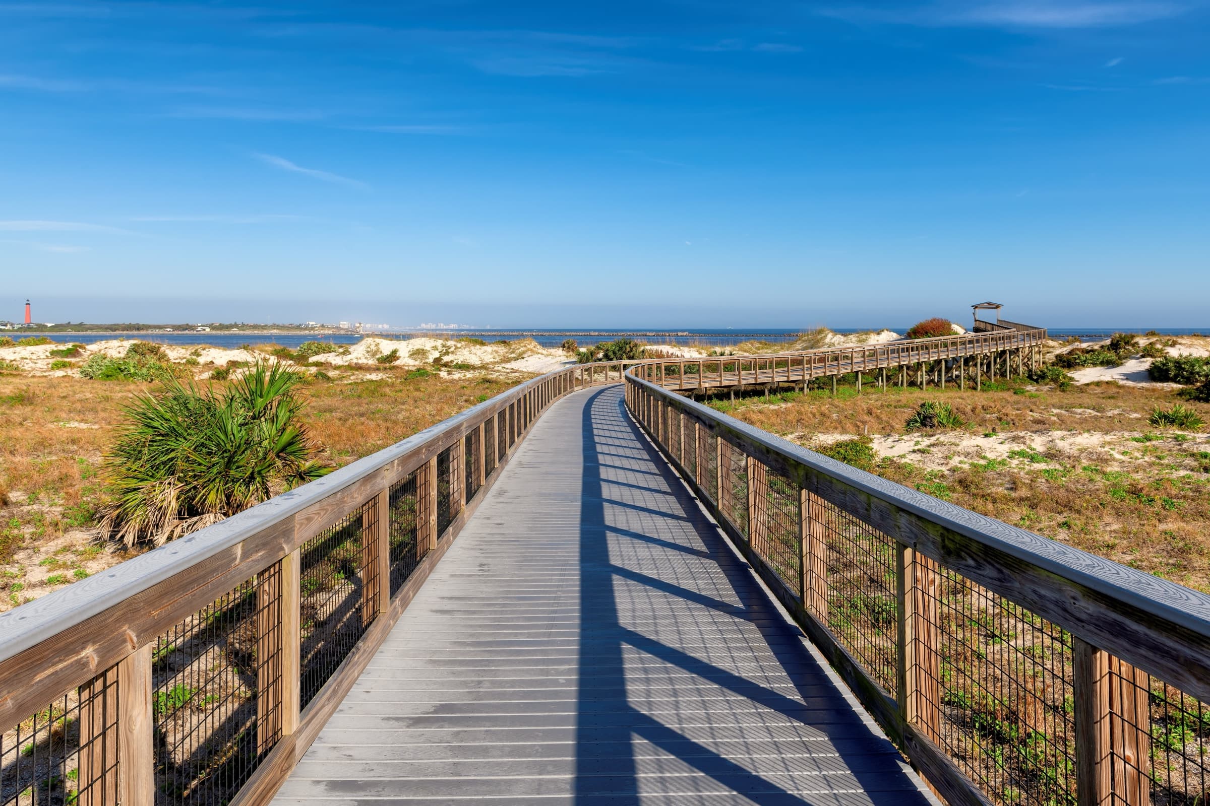 Elevated boardwalk winding through coastal dunes and sea oats at Smyrna Dunes Park in New Smyrna Beach, Florida