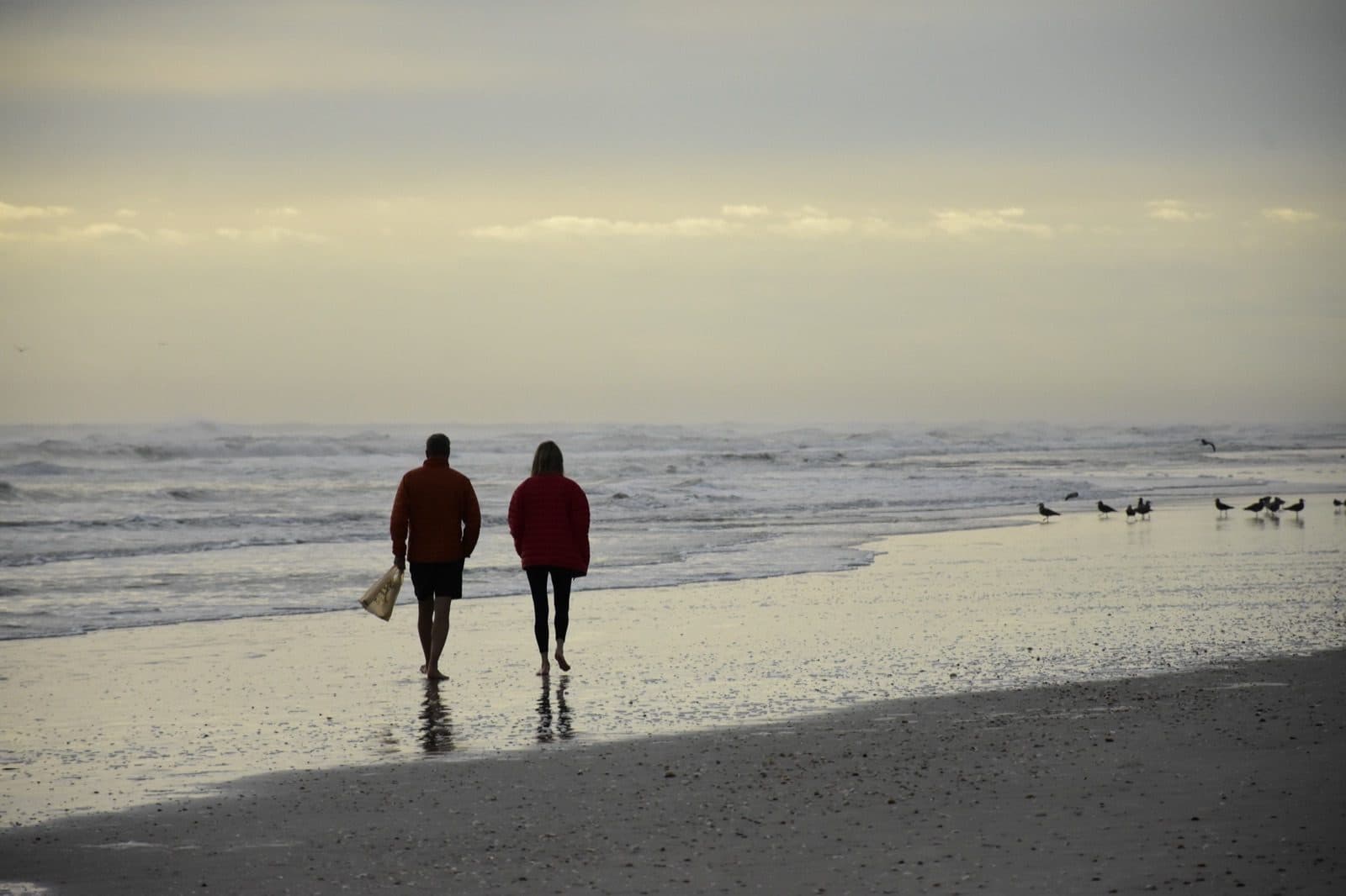 Couple walking along the shoreline at sunset in New Smyrna Beach