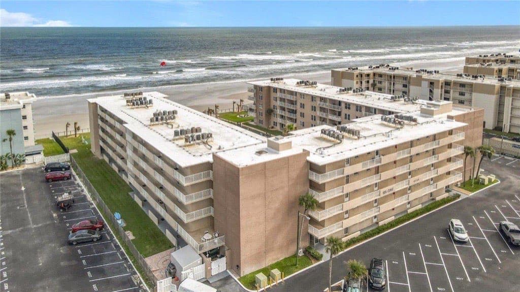 Aerial view of Sea Coast Gardens condominium building with Atlantic shoreline and parking in New Smyrna Beach