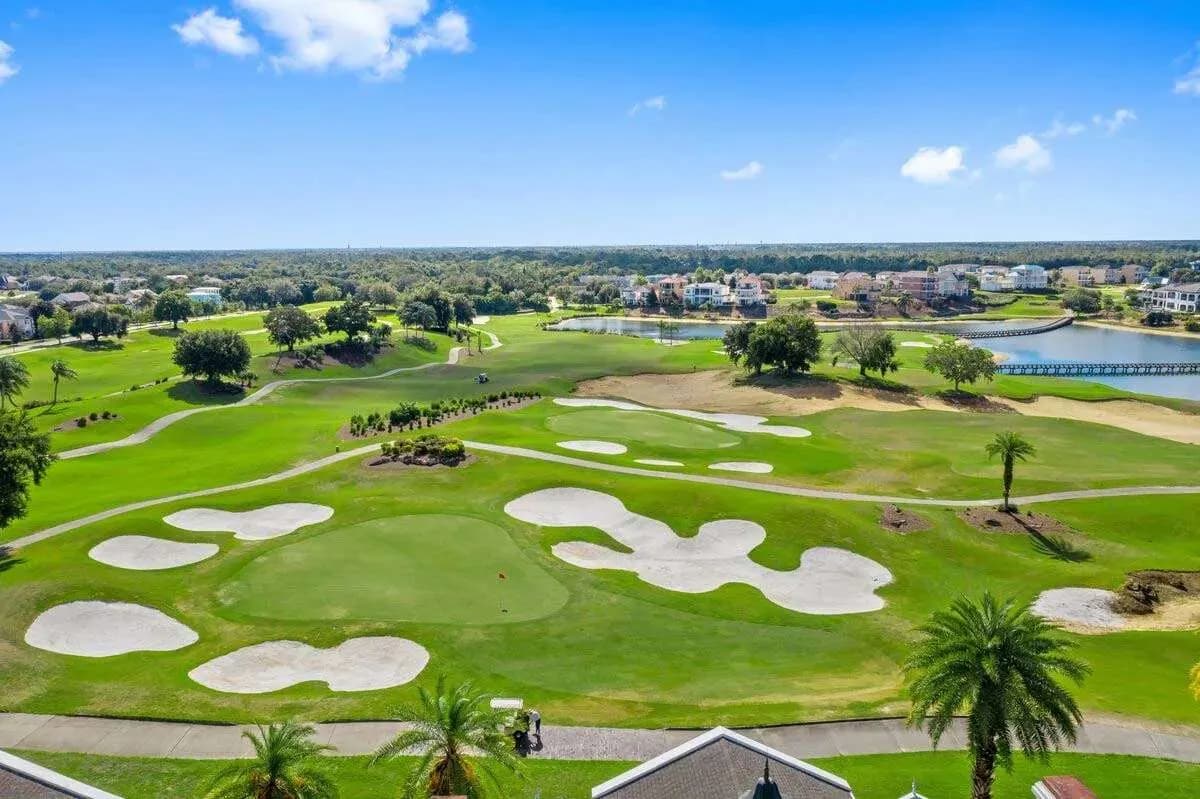 Aerial view of the Reunion Resort championship golf course, with manicured fairways, sand bunkers, a lake and resort residences beyond.