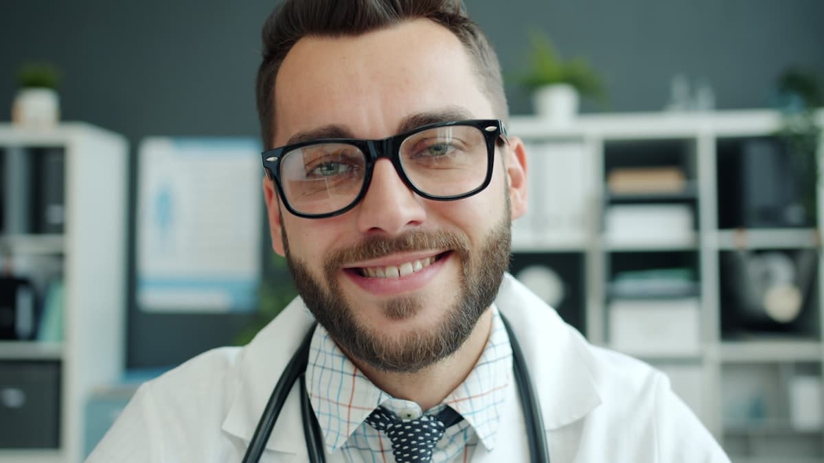 Smiling doctor in a white coat with a stethoscope in an office