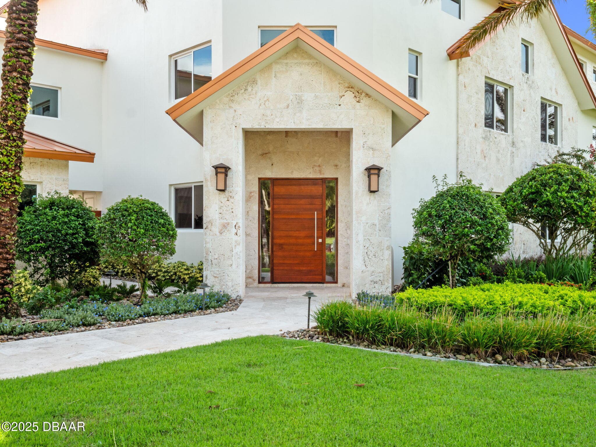 Coral stone entry of a luxury New Smyrna Beach residence with manicured landscaping