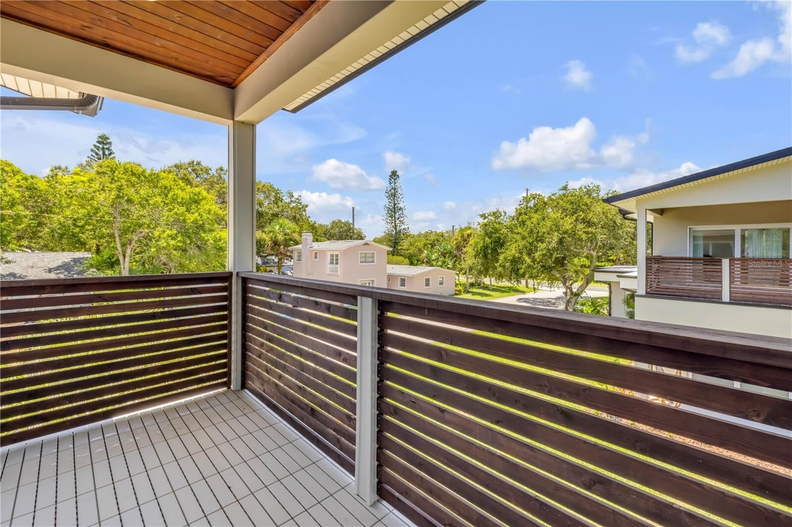 The private balcony off the guest apartment, with a cable railing and treetop outlook