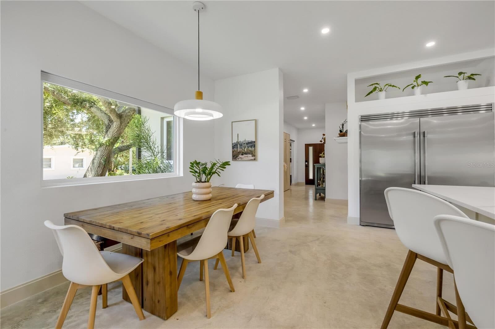 The kitchen and dining area, with a marble island, custom cabinetry and a dining table beneath a pendant light